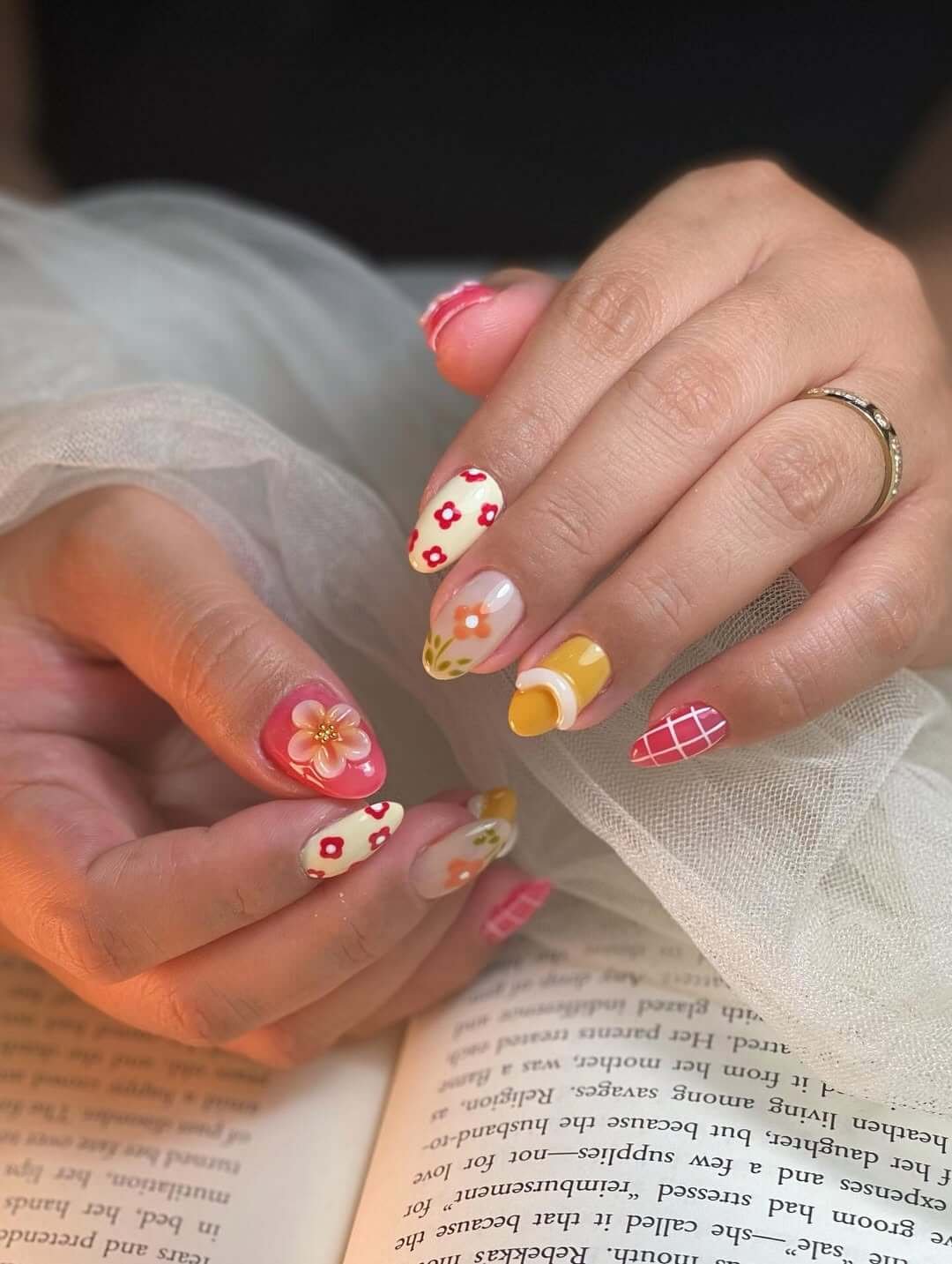 Almond nails with daisy florals, checkerboard tips, and juicy color-blocked accents for a fresh picnic look.