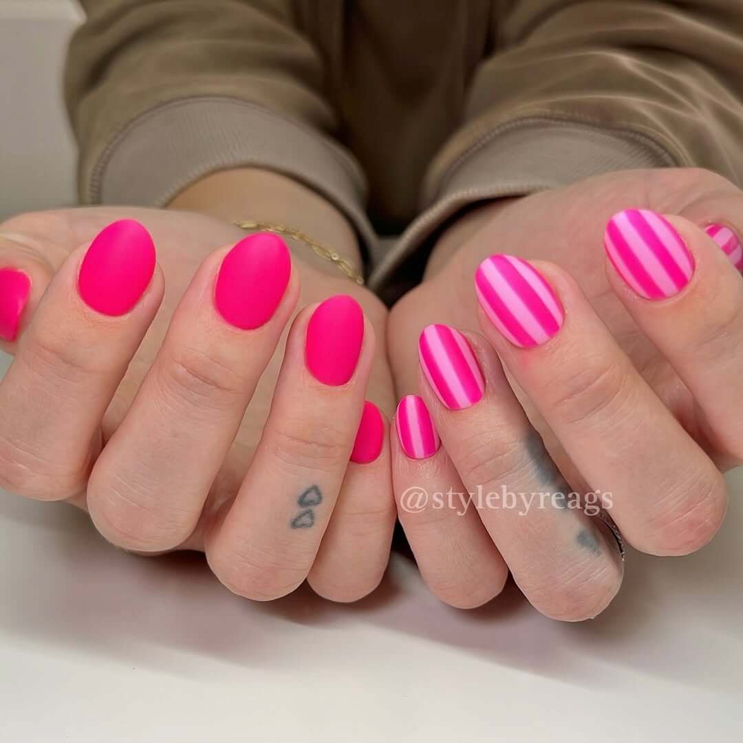 Oval nails in matte hot pink with bold candy-like stripes for a retro pop art vibe.