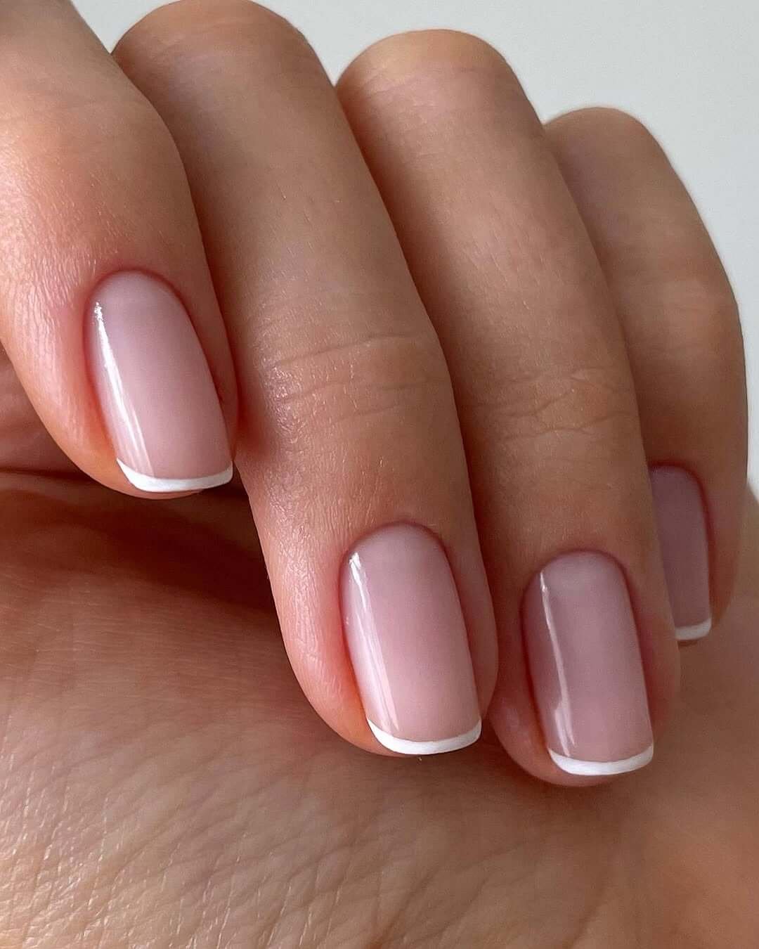 Short square nails with soft pink bases and crisp white French tips for a timeless manicure style.