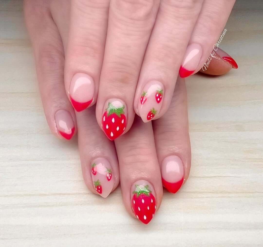 Short almond nails with red French tips and hand-painted strawberries for a fresh and flirty look.