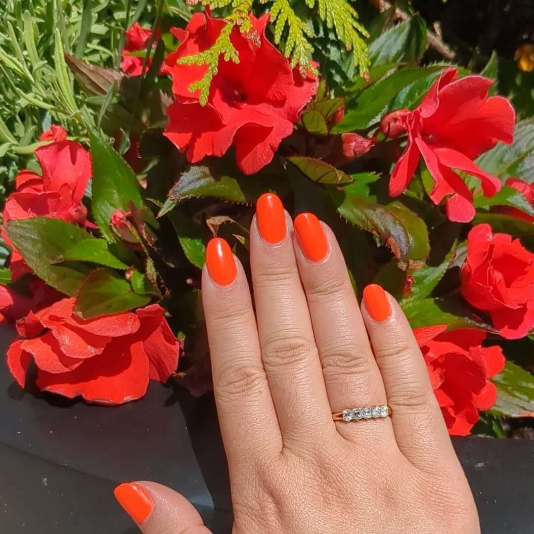 Oval nails in electric coral red for a bold, sun-kissed summer look.