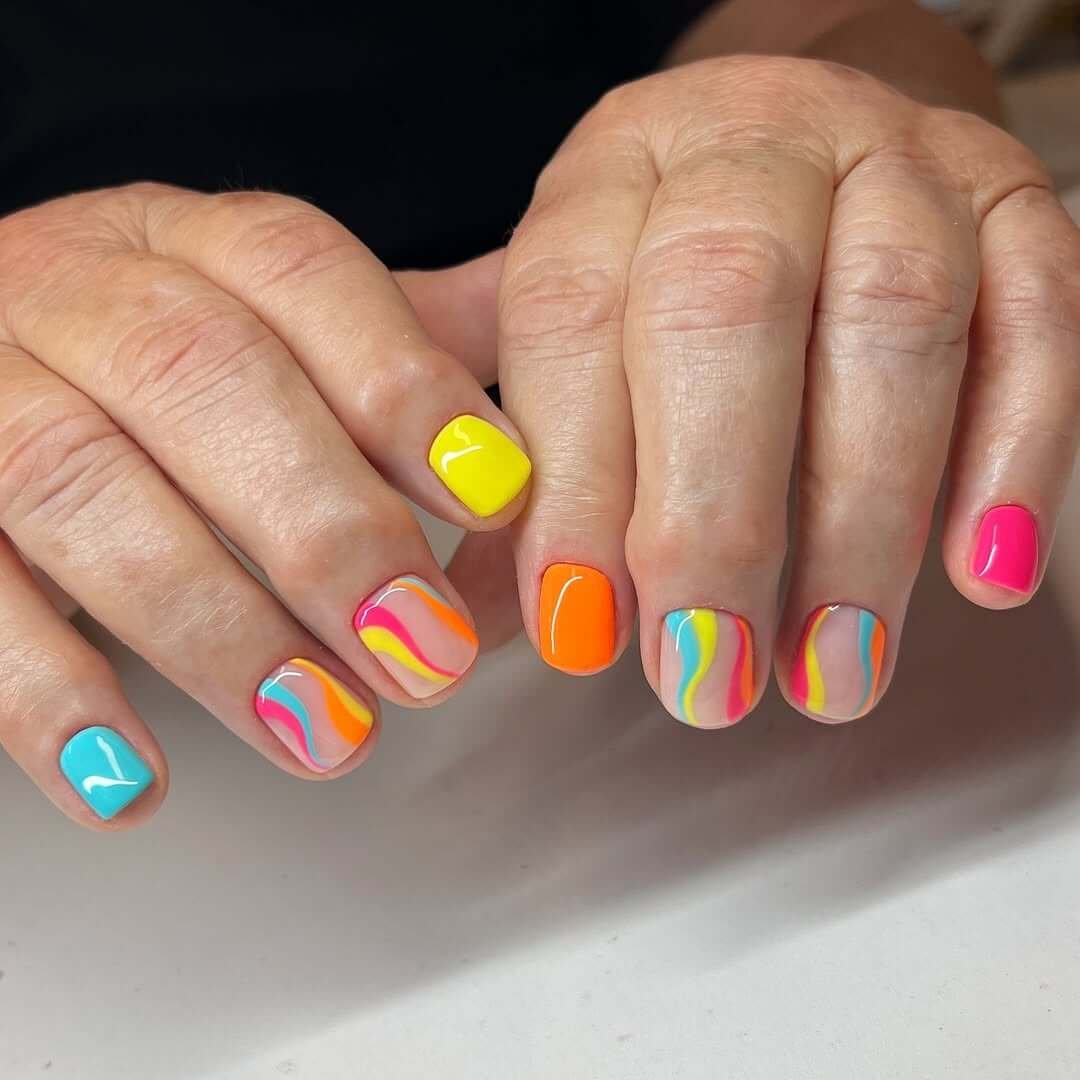 Short square nails with colorful neon swirls and a glossy finish for a festival-ready summer style.