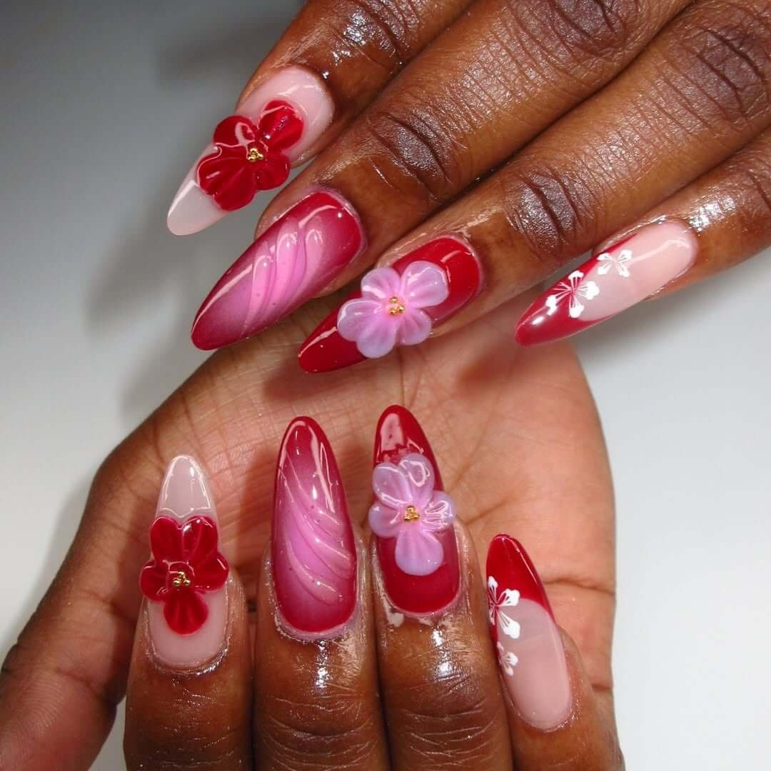 Stiletto nails with red gradient, 3D flowers, and a glossy high-drama finish.
