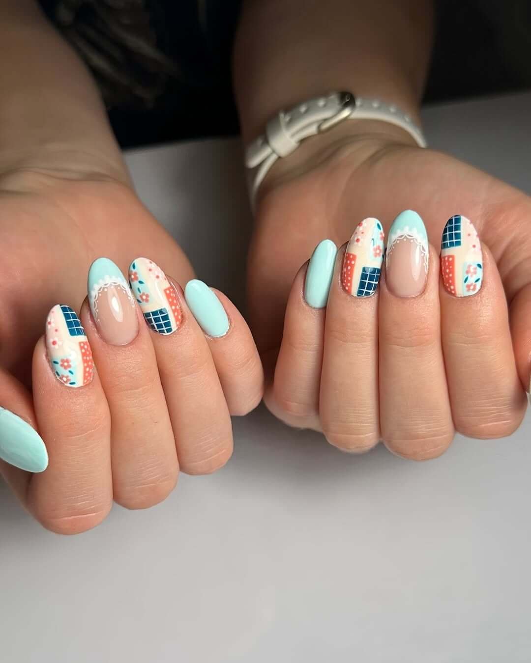 Almond nails with soft blue tones, patchwork patterns, florals, and lace for a cottagecore summer look.