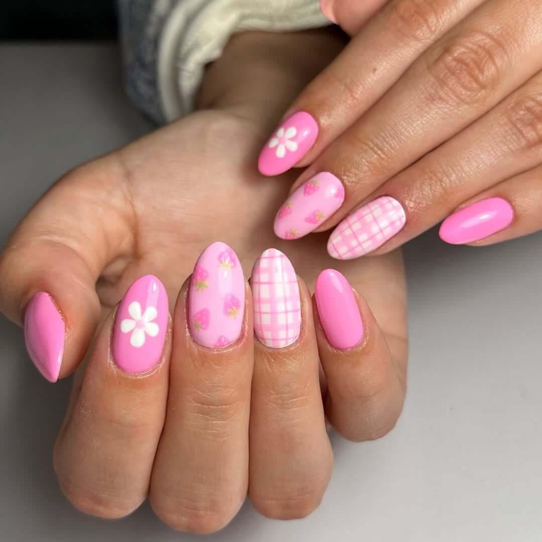 Short almond-shaped nails with gingham print, strawberries, and daisies for a cute picnic-inspired summer design.