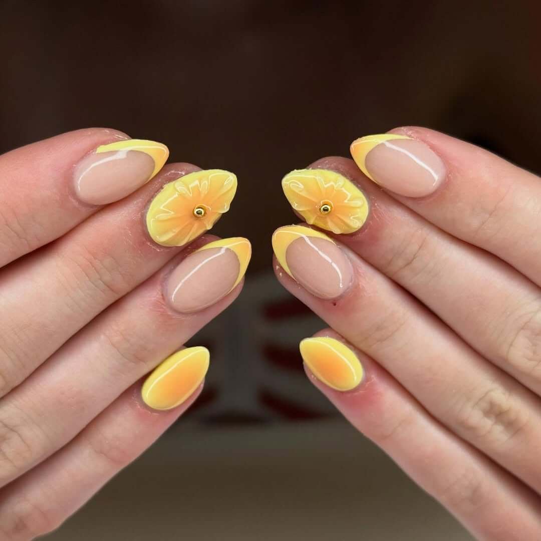 Almond nails with soft yellow French tips and 3D sunflower petals for a bright, joyful mani.